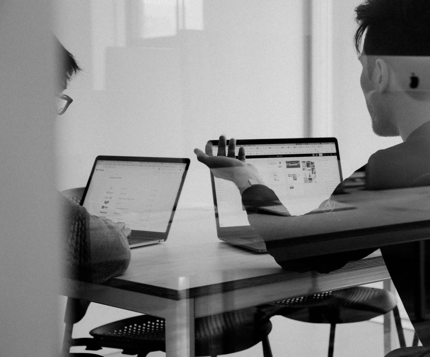 Mit dem Kunden im Gespräch. Zwei Personen sitzen mit ihren Laptops an einem Tisch und unterhalten sich angeregt.